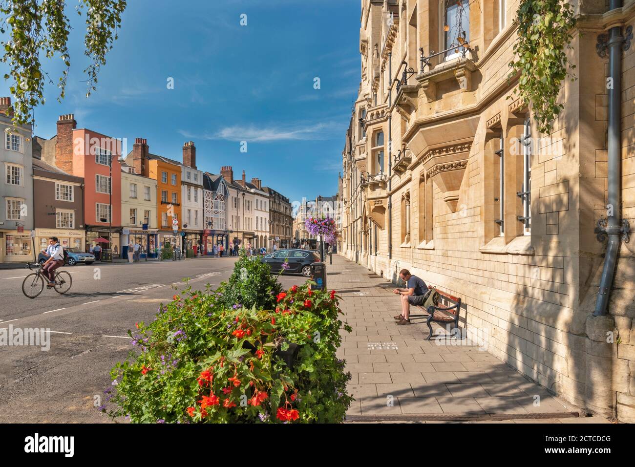 OXFORD CITY ENGLAND BALLIOL COLLEGE ON THE RIGHT IN  BROAD STREET AND ROW OF COLOURED HOUSES FLOWERS AND SHOPS IN SUMMER Stock Photo