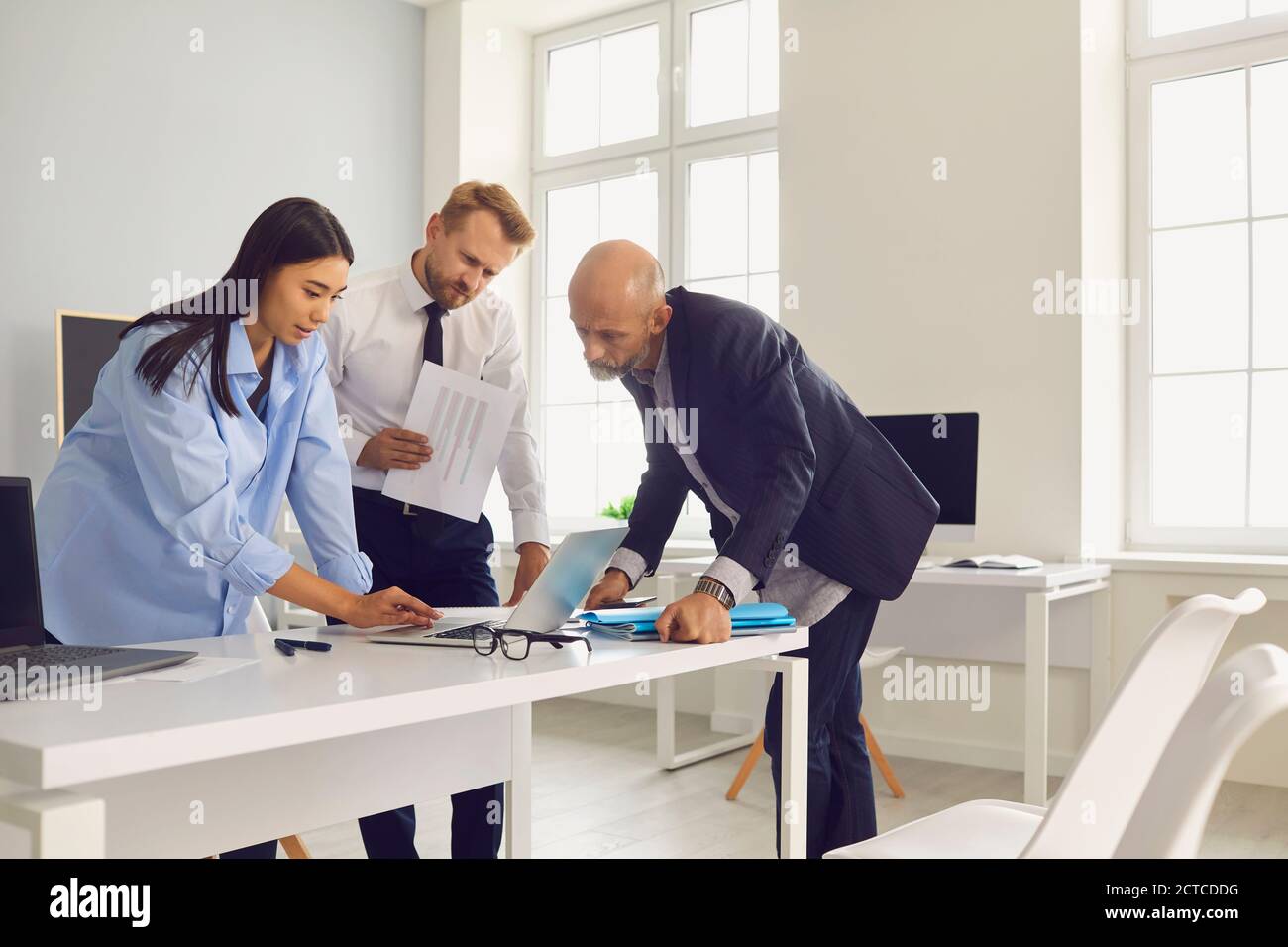 Business team looking at laptop screen analyzing research data while working on project together Stock Photo