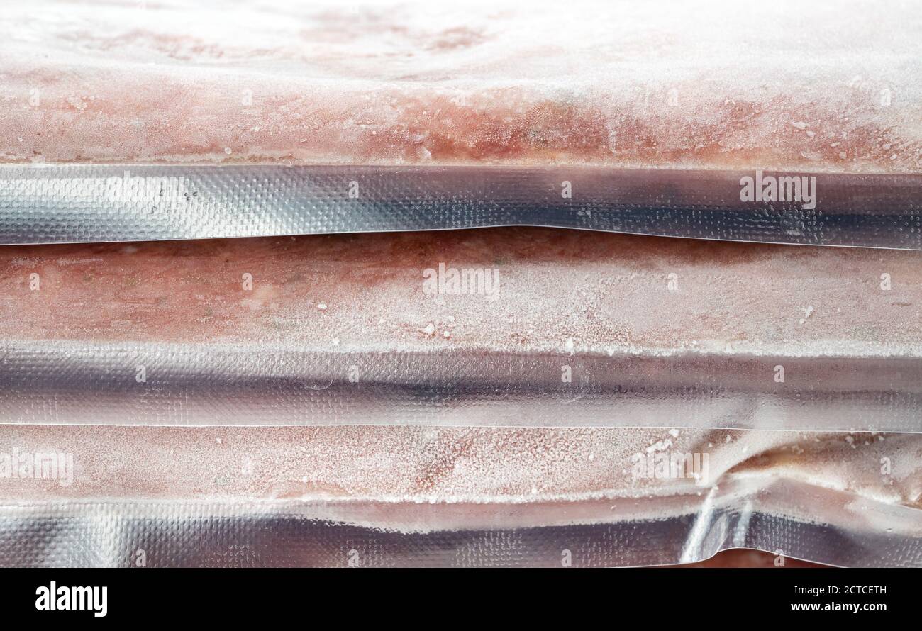 Close up of frozen meat packages on top of each other. Plastic food packages, vacuum sealed. Ground chicken inclusive backs, necks, liver and heart. Stock Photo