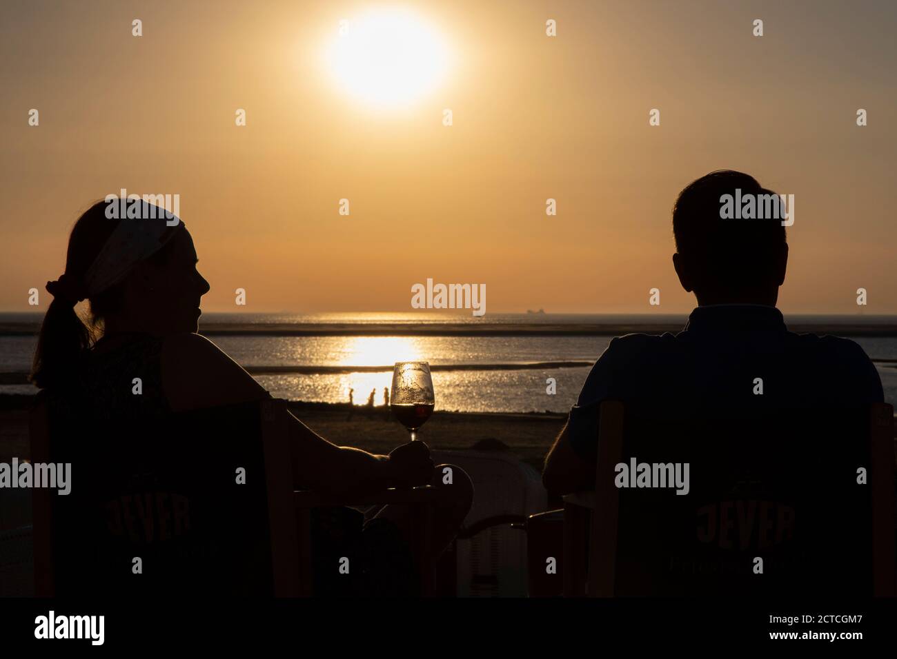 Silhouette of young couple on promenade watching sunset on  Borkum Island, Frisia, Lower Saxony, Germany, Europe. Stock Photo