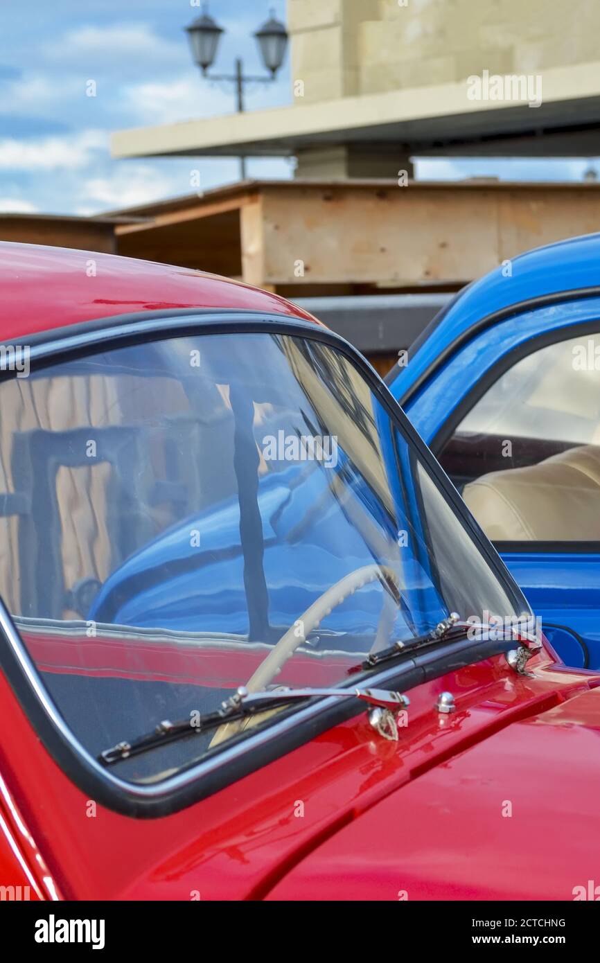 Car hood and windshield of a red vintage car on the background of a blue car close-up. Stock Photo