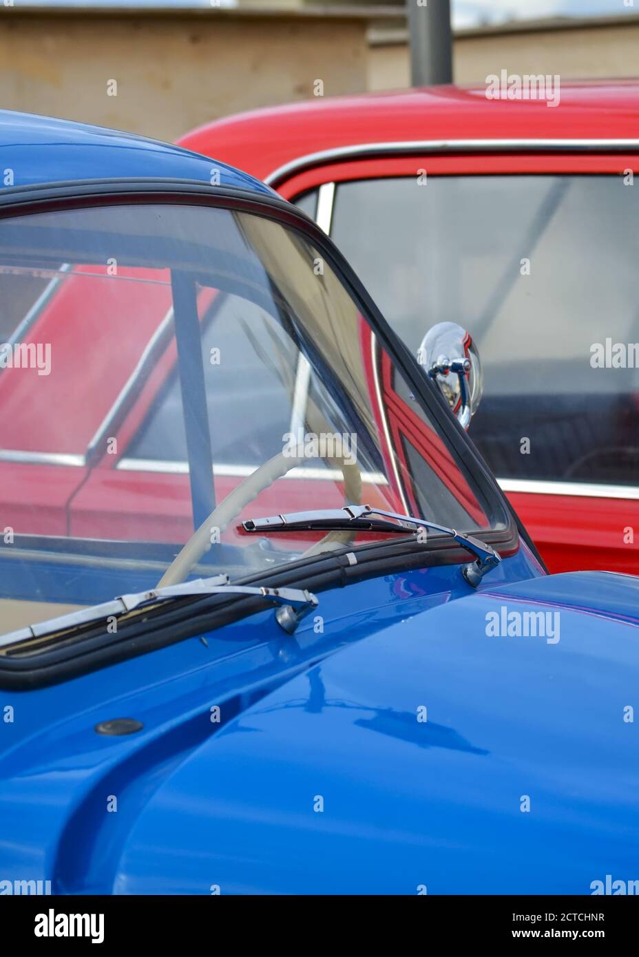 Car hood and windshield of a blue vintage car on the background of a red car close-up Stock Photo