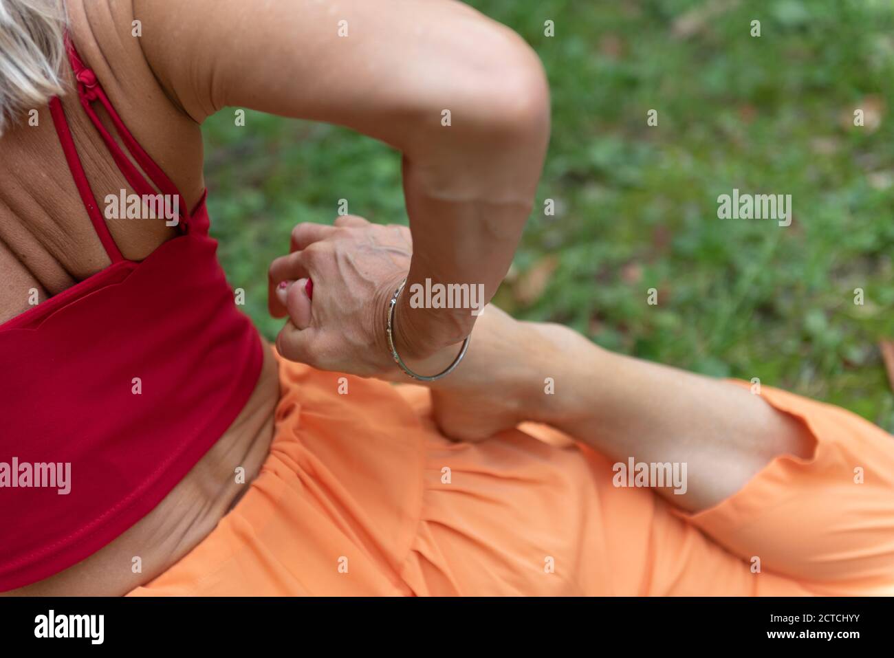 Woman practicing yoga in nature. Part of the body. Arm and leg in the foreground. Performs a pigeon pose and further stretches your quads. Stock Photo