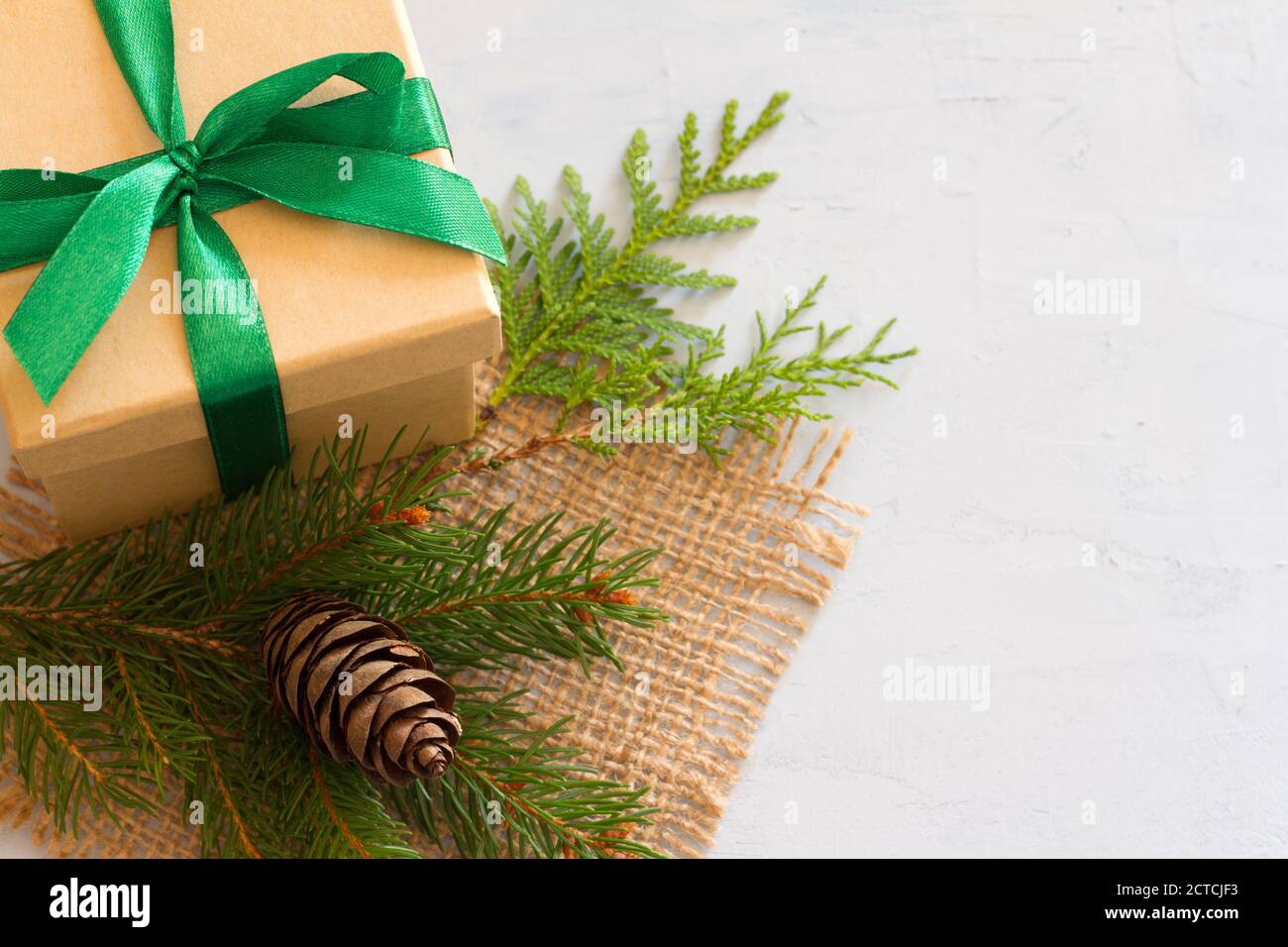 Christmas composition. Christmas gift, jute, pine cone and fir twigs on light background Stock Photo