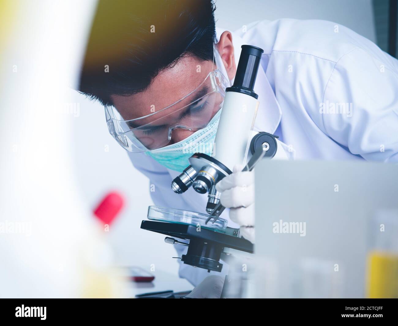 Asian male scientist Is working seriously Chemistry experiment With a microscope In the laboratory, the color tone image. Stock Photo