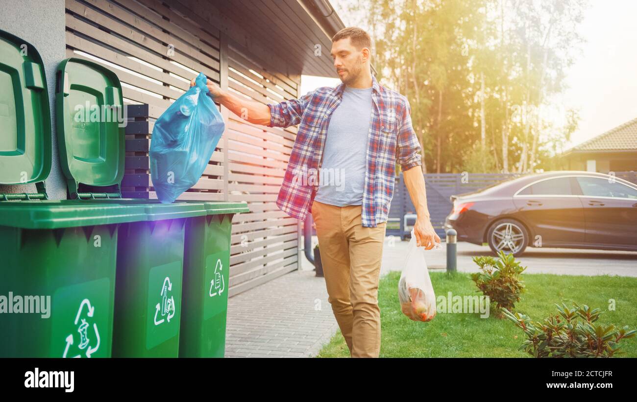 Caucasian Man is Throwing Away Two Plastic Bags of Trash next to His House. One Garbage Bag is Sorted with Biological Food Waste, Other with Stock Photo