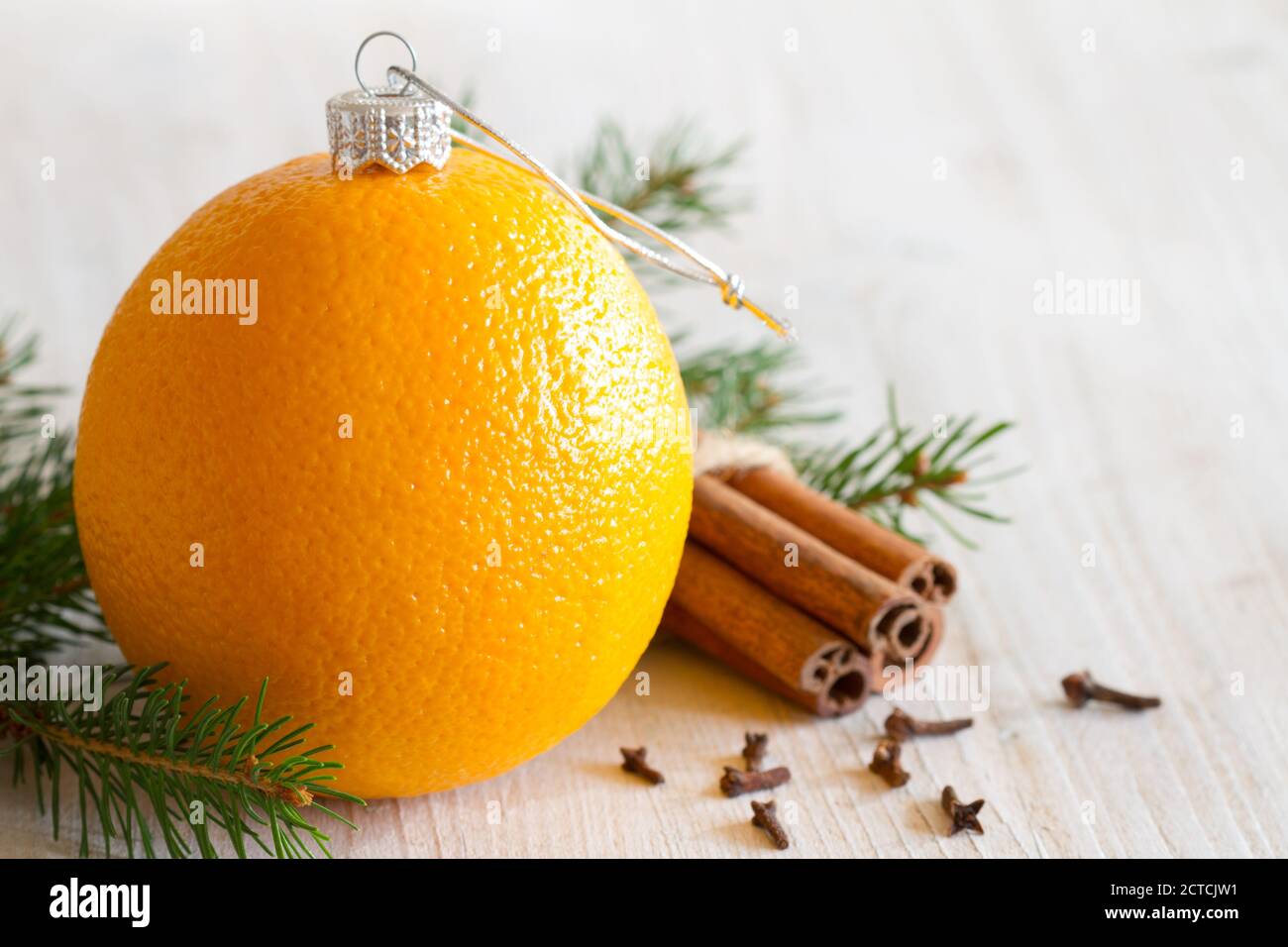 Abstract orange christmas ball, with cinnamon, cloves and christmas tree in background Stock Photo