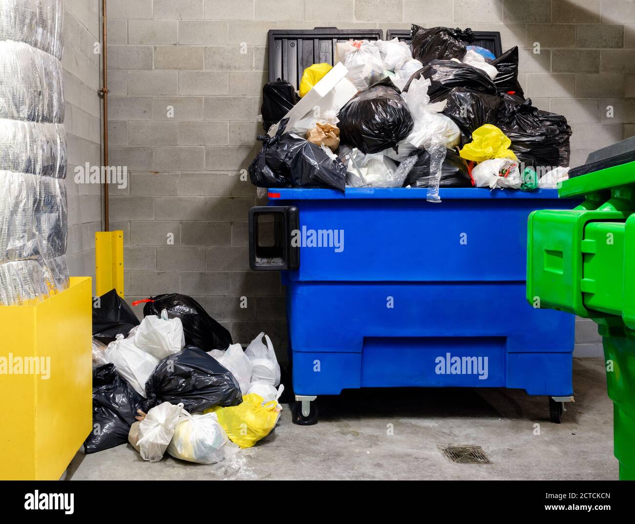 Overloaded household garbage container in garbage room of residential building. Waste management company has missed pickup due to snowstorm. Stock Photo