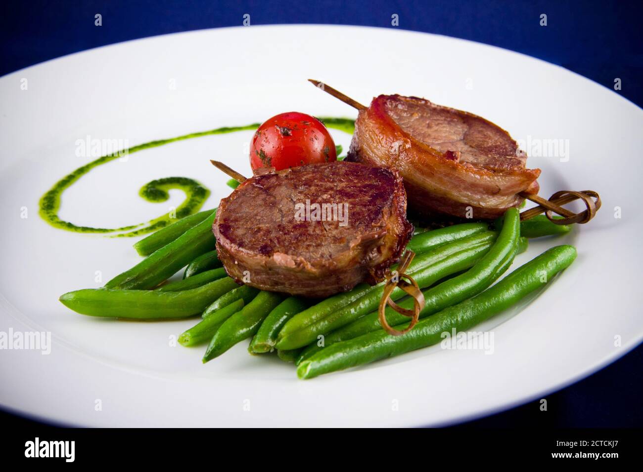 Grilled pork medallions on skewers with string beans and whole tomatoes