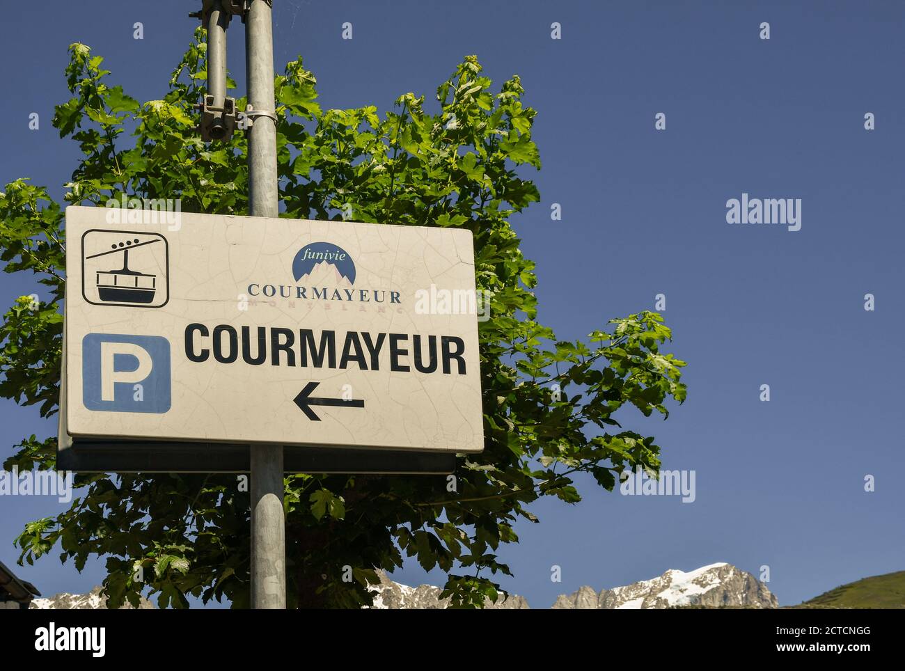 Indication sign of the Courmayeur Cableway with snowcapped peaks of the Mont Blanc massif in the background in summer, Courmayeur, Aosta, Italy Stock Photo