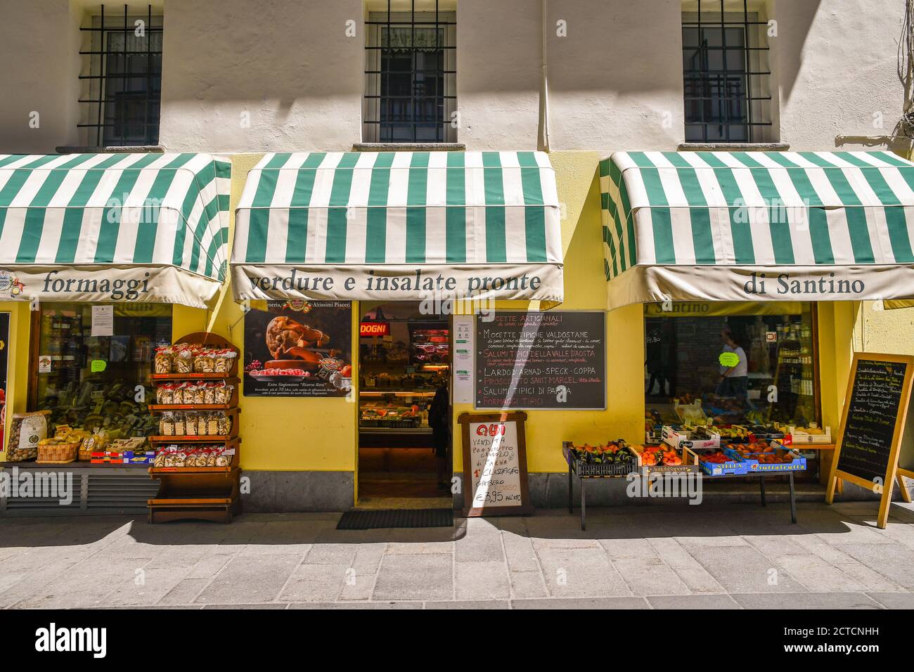 Exterior of a grocery store selling typical products with fruits and vegetables displayed on the sidewalk in the Alpine town, Courmayeur, Aosta, Italy Stock Photo