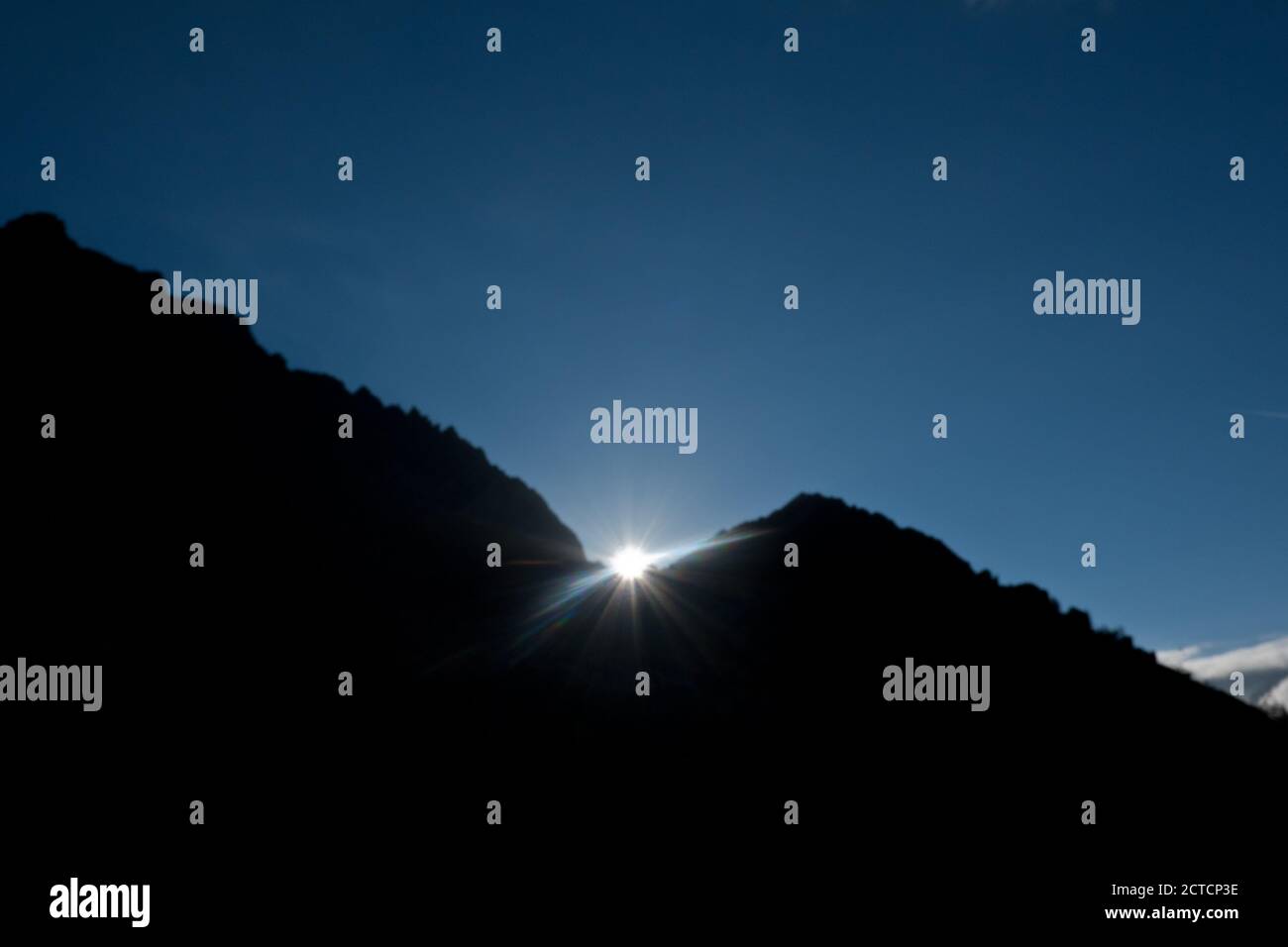 Sunrise over mountain silhouette in dark blue sky in the Alps Stock Photo