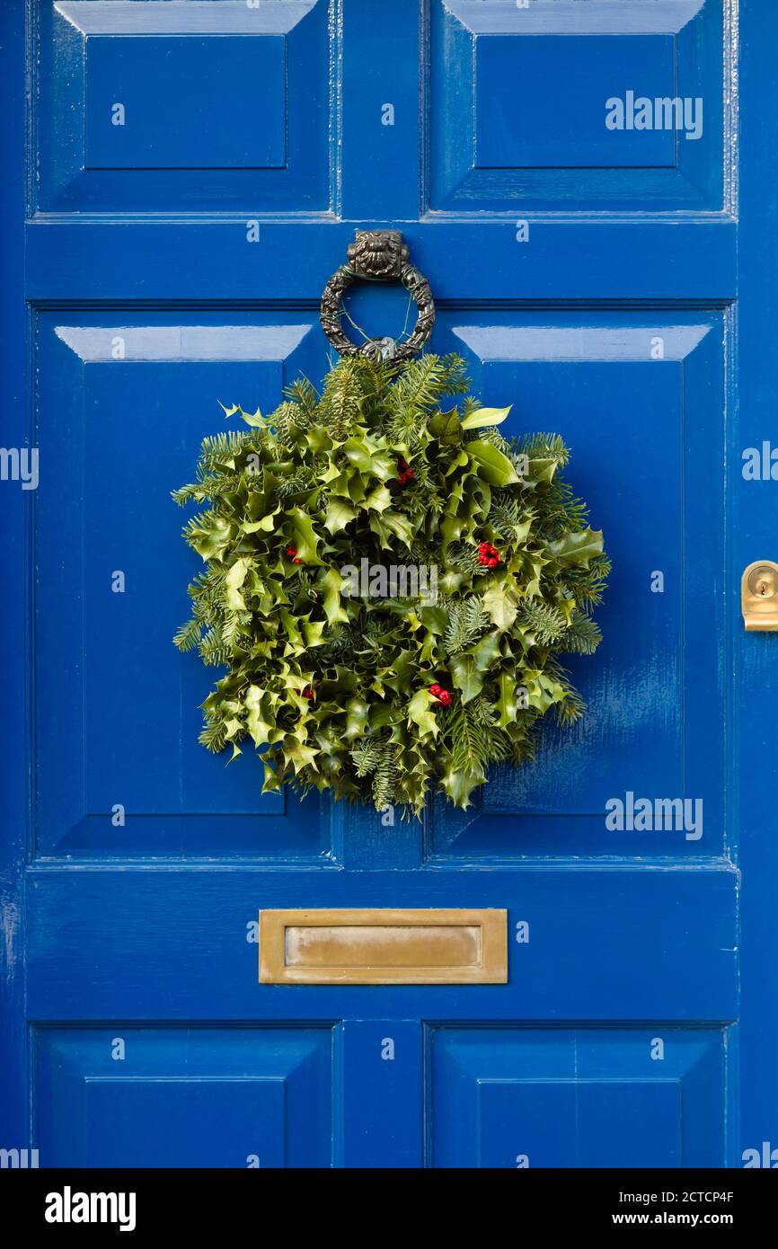 Detail of blue front door with Christmas garland wreath made from holly Stock Photo