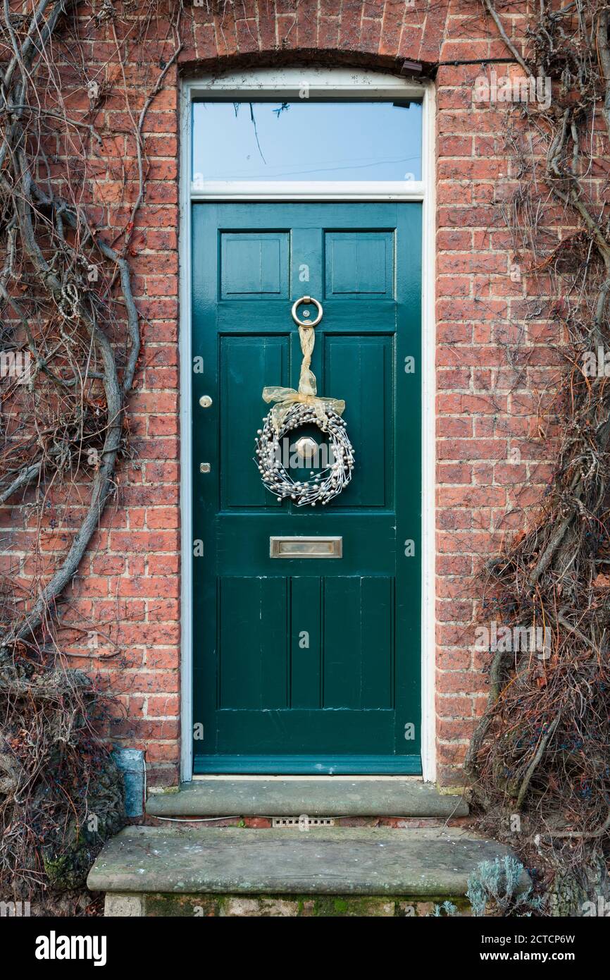 WINSLOW, UK - December 29, 2019. Front door outside a house in UK at Christmas time, door painted green, teal, with xmas wreath Stock Photo
