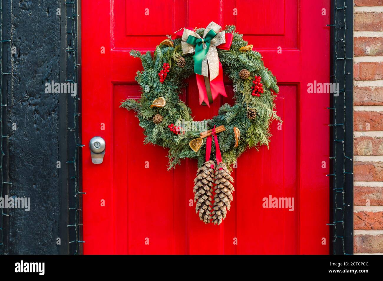 Front door to an English home painted red with a Christmas wreath, Xmas Garland Stock Photo