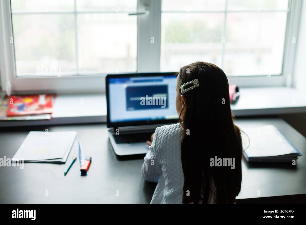 Little girl studying online using her laptop at home Stock Photo - Alamy