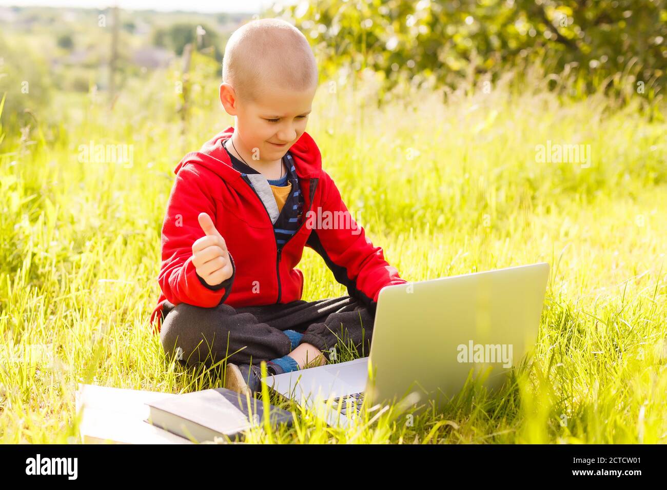 Learning Boy With Computer Distance learning. Boy learns autdoor laptop. Doing homework on grass ...