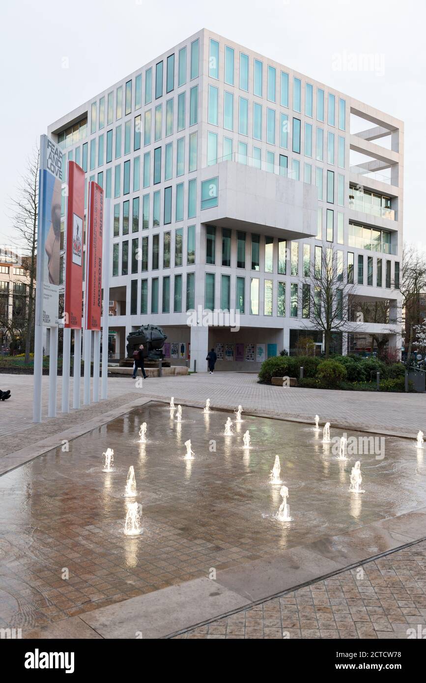 The Design Museum, London, multi story building with white detailing, courtyard and banners, small water jets. Stock Photo