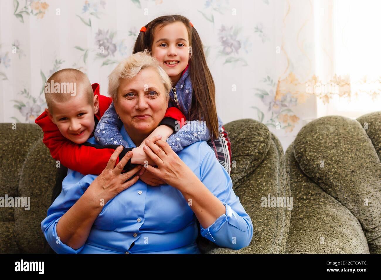 Grandmother and grandchildren sitting together on sofa in living room Stock Photo