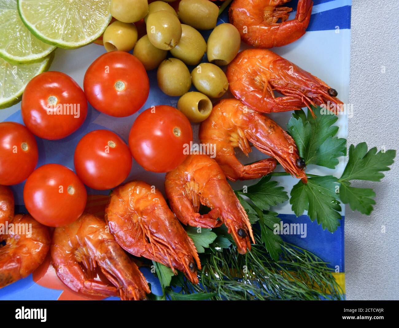 Cooked shrimp with fresh herbs, olives, lime and tomatoes Stock Photo