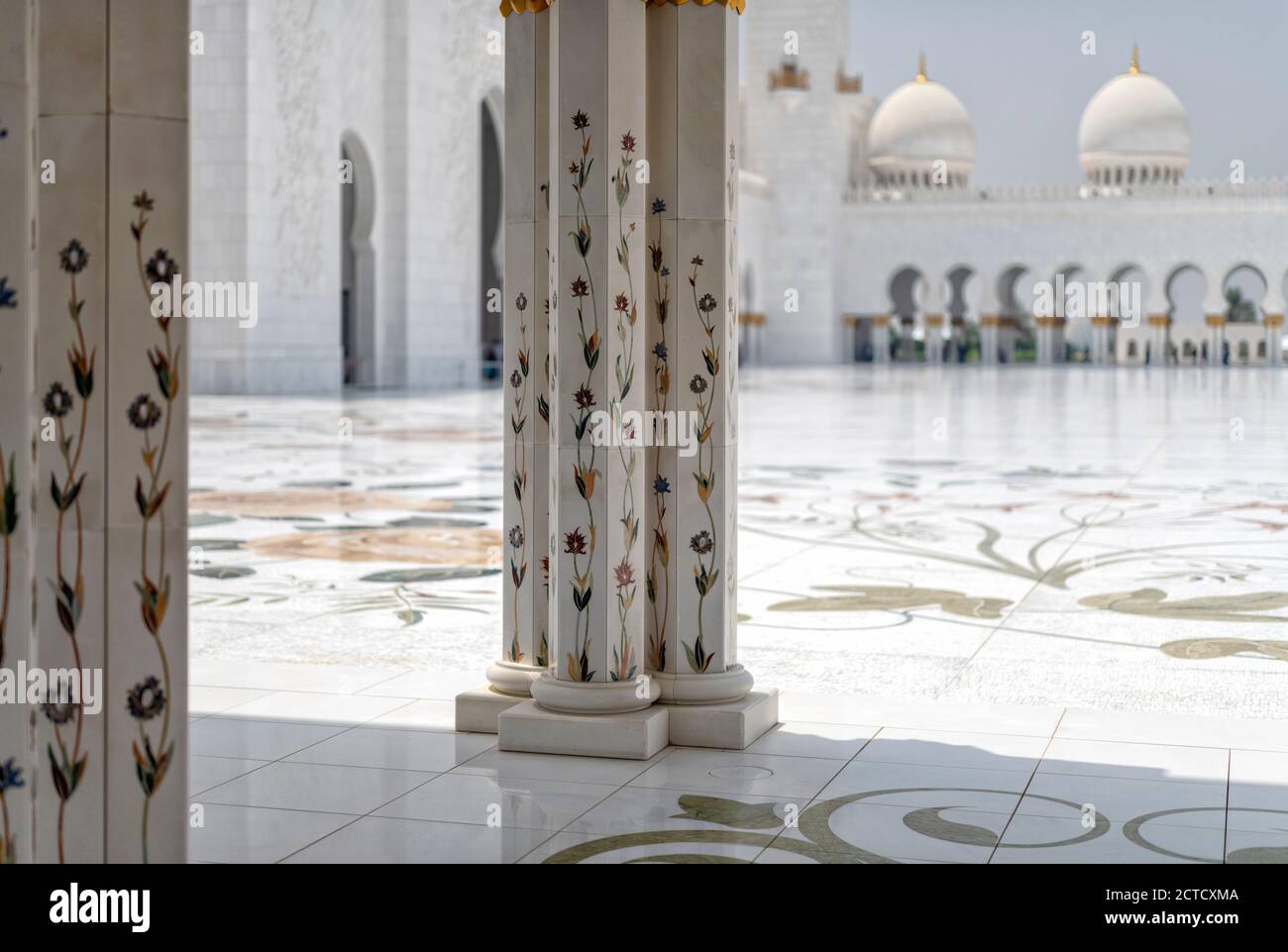 A day shot from the archway inside the Sheikh Zayed Grand Mosque, Abu Dhabi looking into the inner courtyard. Architectural features of marble columns with marble floral design. Mosque completed 2007. Stock Photo