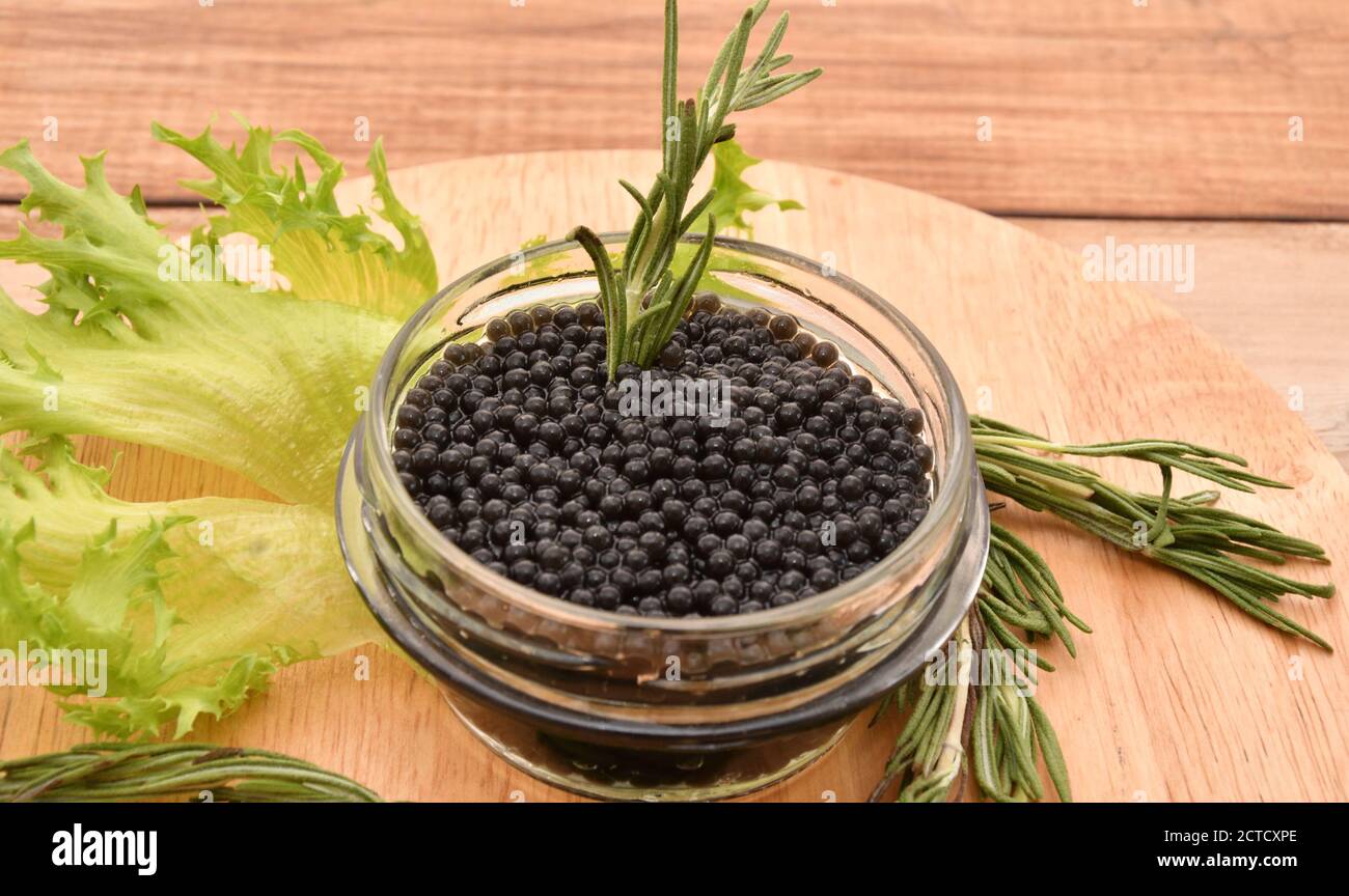 Black caviar with fresh herbs on a cutting board Stock Photo