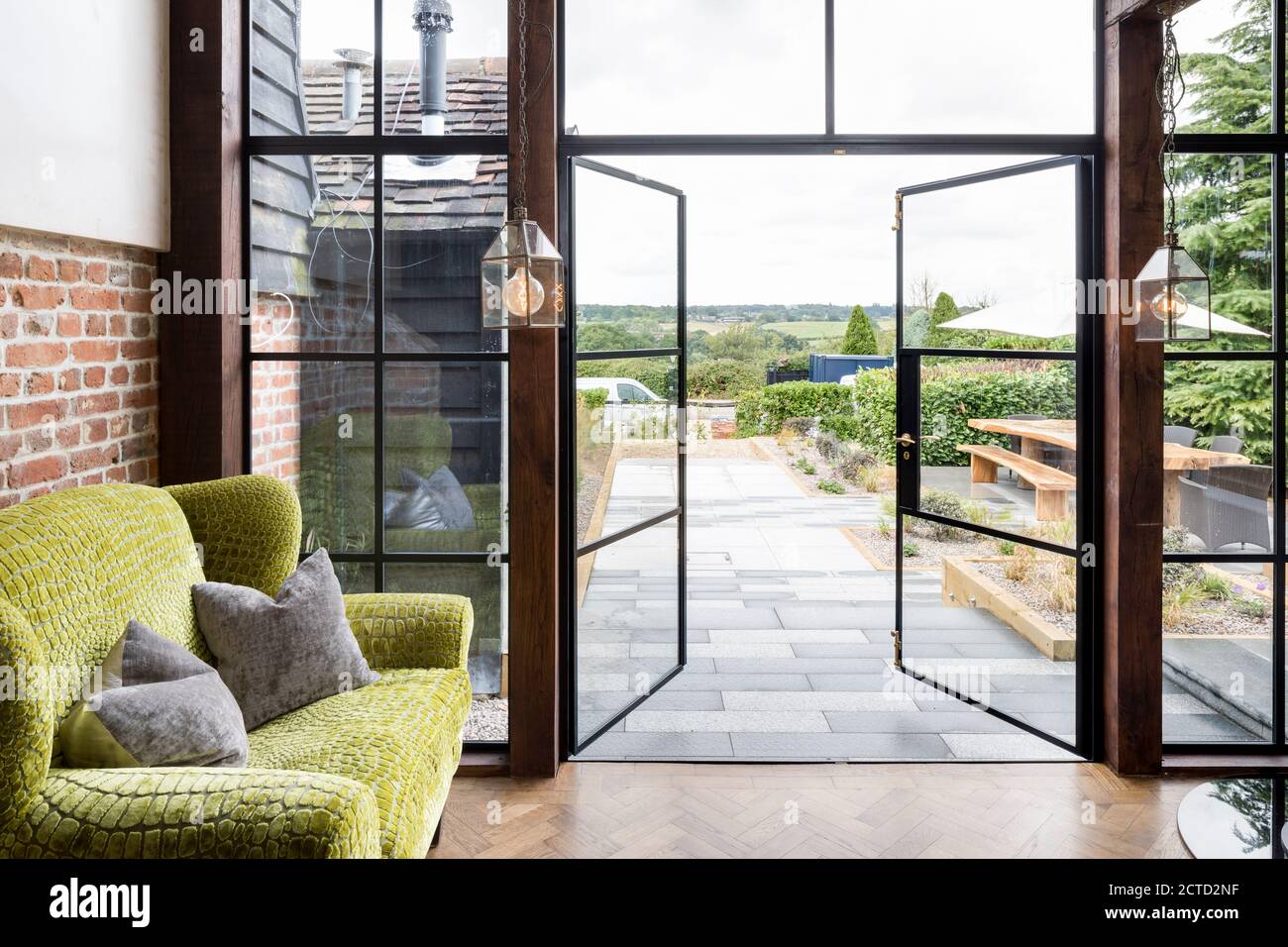 Sofa next to open doors leading out to the garden of a converted barn