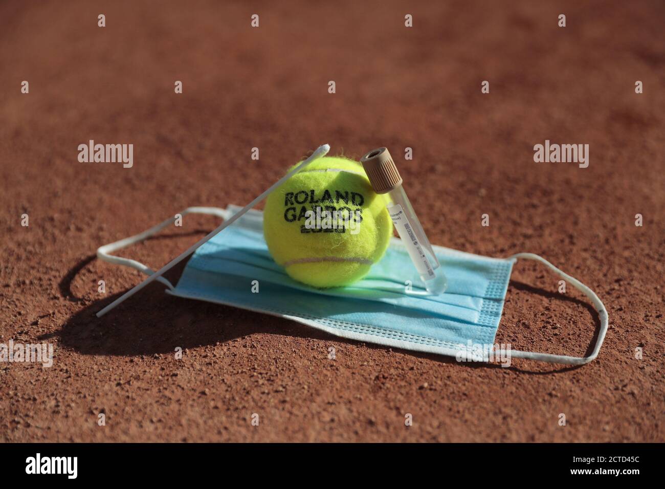Illustration of official tennis ball Roland Garros 2020 by Wilson on the clay of Philippe Chatrier court over protector mask with swab sample with tub Stock Photo