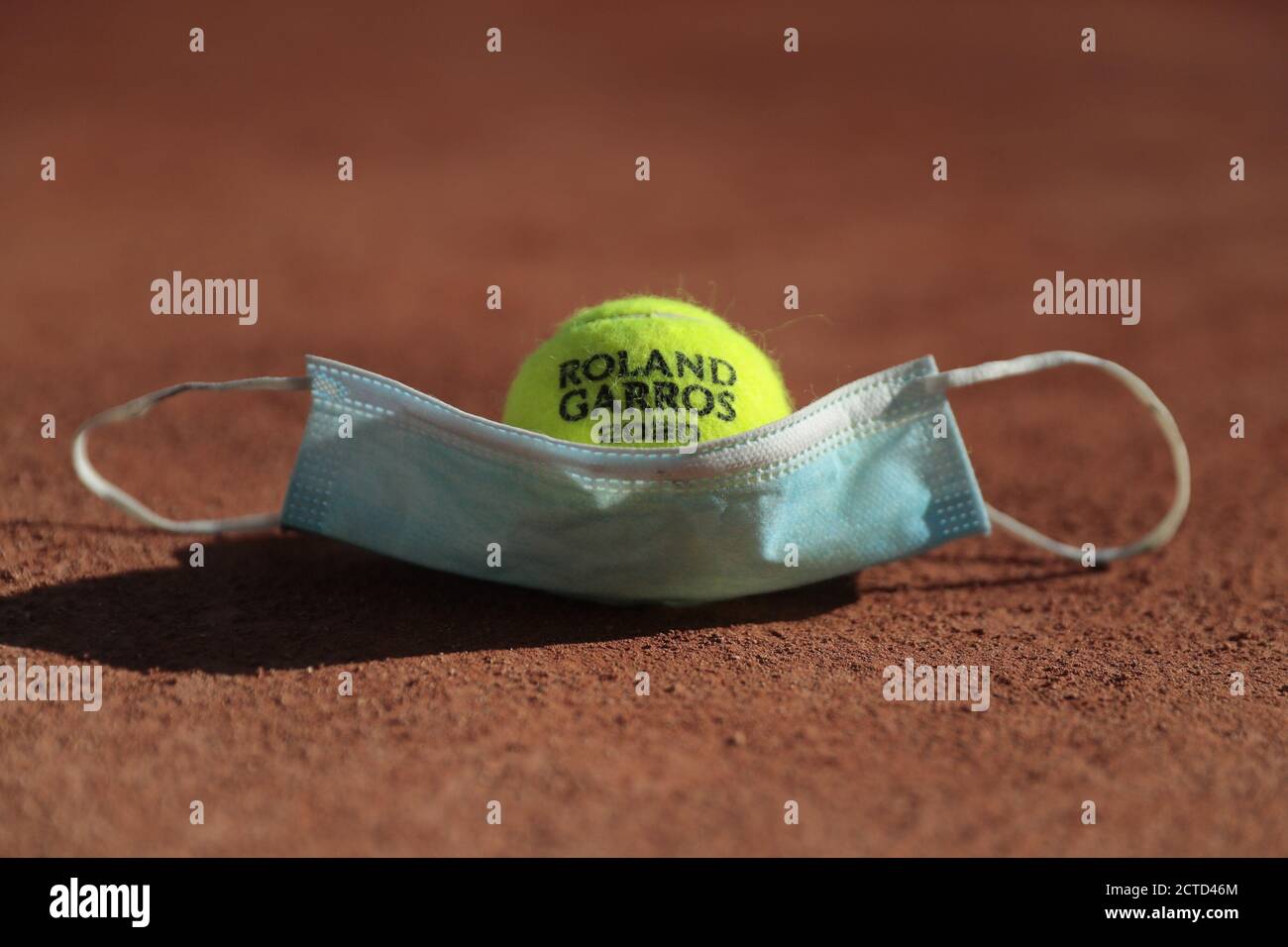 Illustration of official tennis ball Roland Garros 2020 by Wilson over protector mask on clay of Philippe Chatrier court under the CoVid health crisis Stock Photo