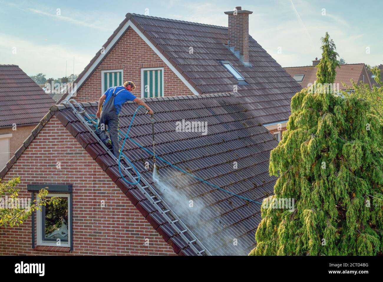 Cleaner with pressure washer at roof house cleaning roof tiles Stock