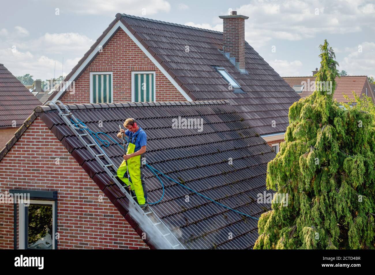 Cleaner with pressure washer at roof house cleaning roof tiles Stock
