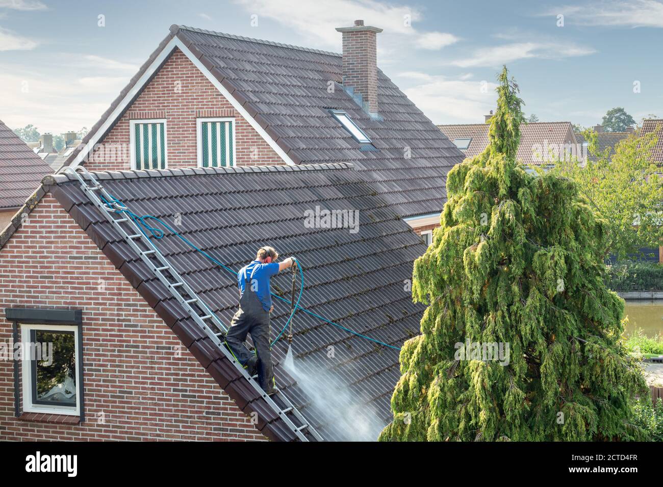 Cleaner with pressure washer at roof house cleaning roof tiles Stock