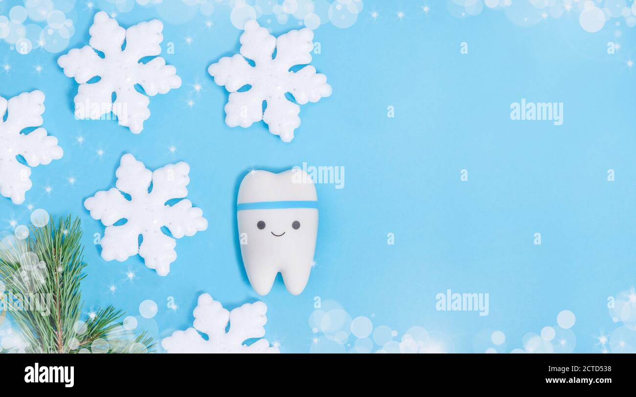 Baner for dentistry for Christmas and New Year with a tooth model on a blue background with a decor from snowflakes with copy space. Stock Photo