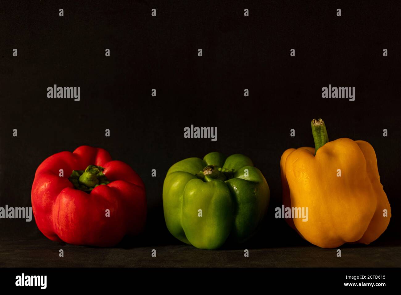 close-up of three bell peppers. red, green and yellow on a dark background Stock Photo