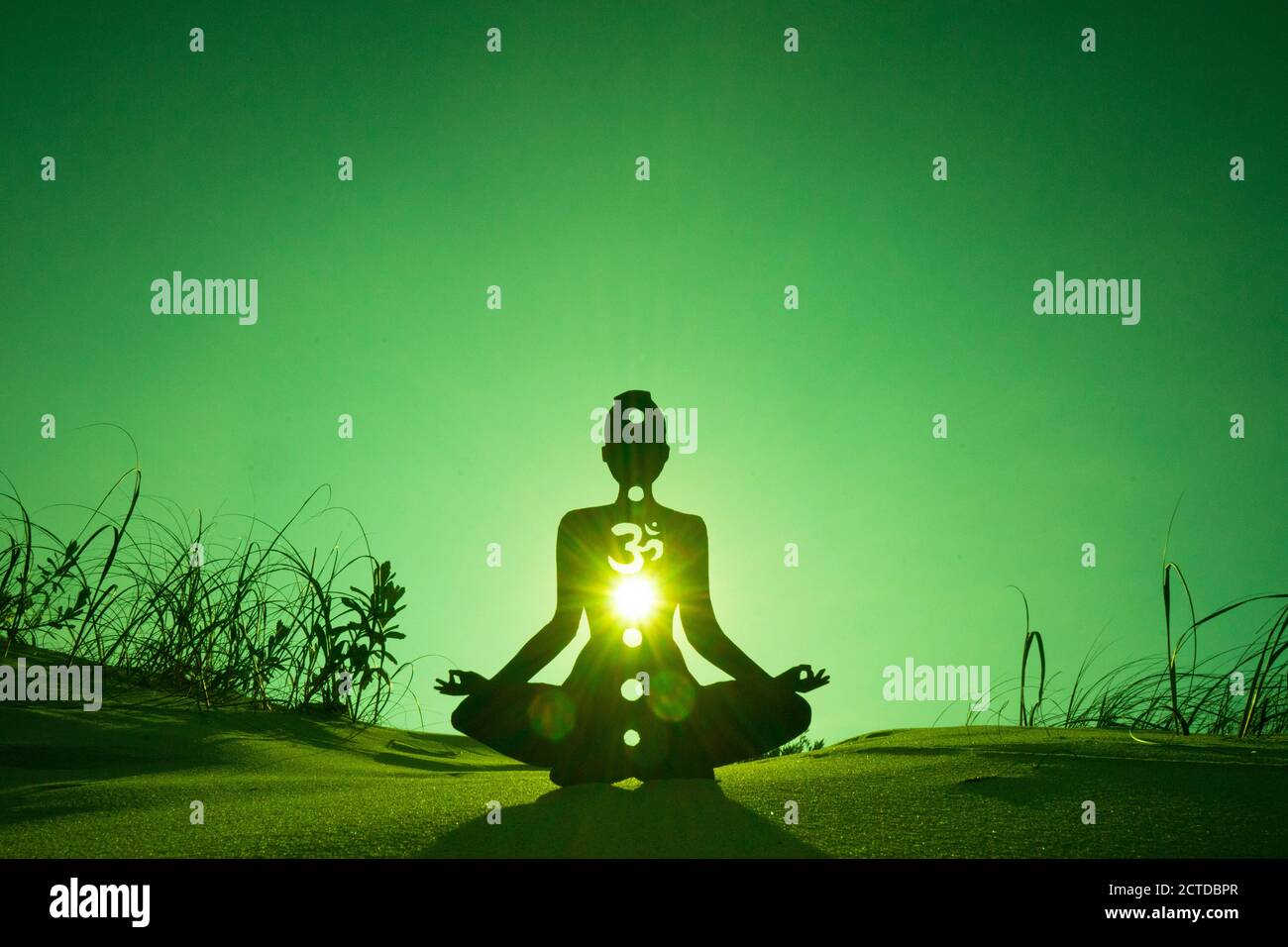 Silhouette of a person doing yoga with the root chakra symbol Stock Photo