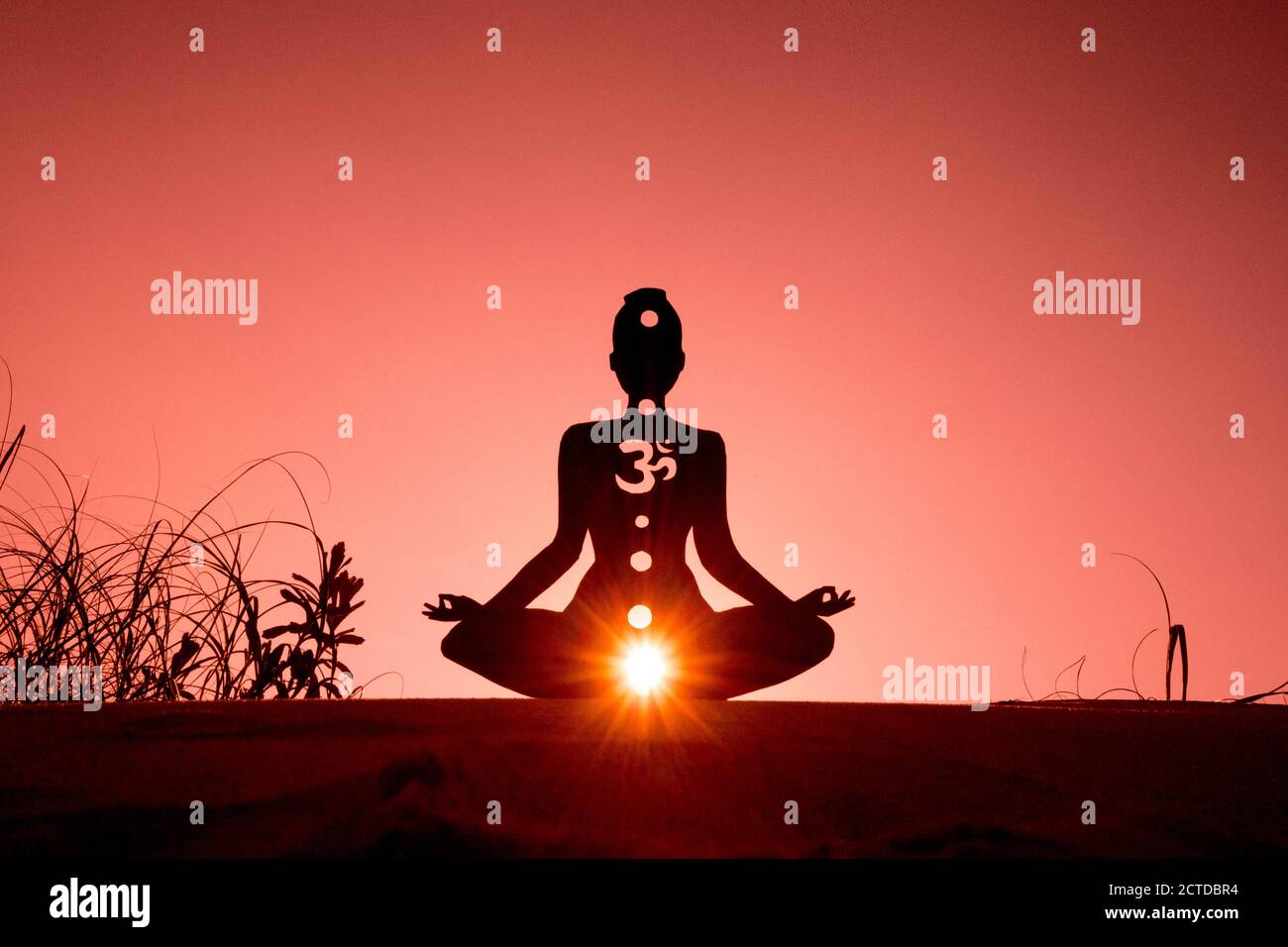 Silhouette of a person doing yoga with the root chakra symbol Stock Photo