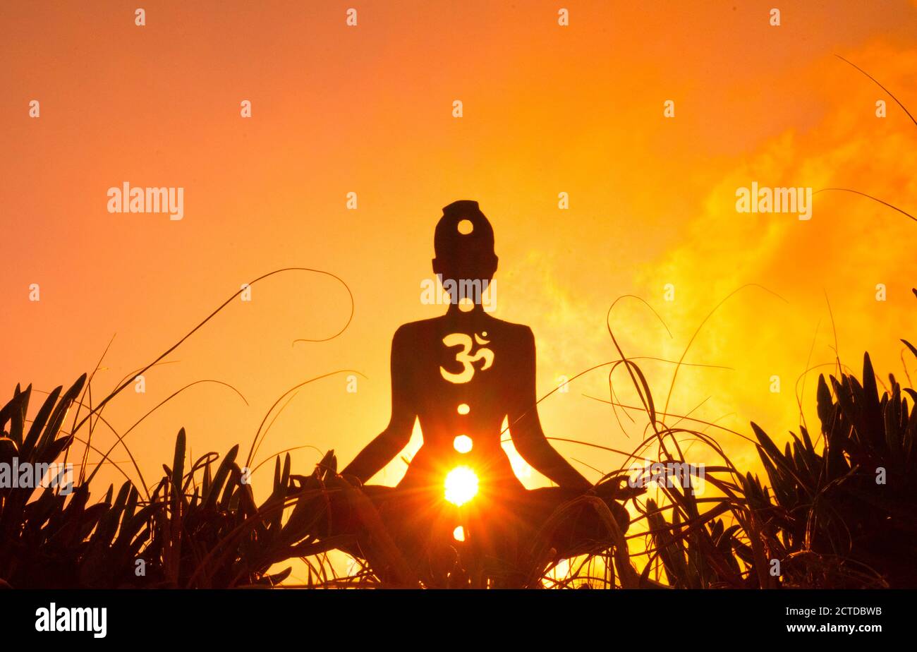 Silhouette of a person doing yoga with the root chakra symbol Stock Photo