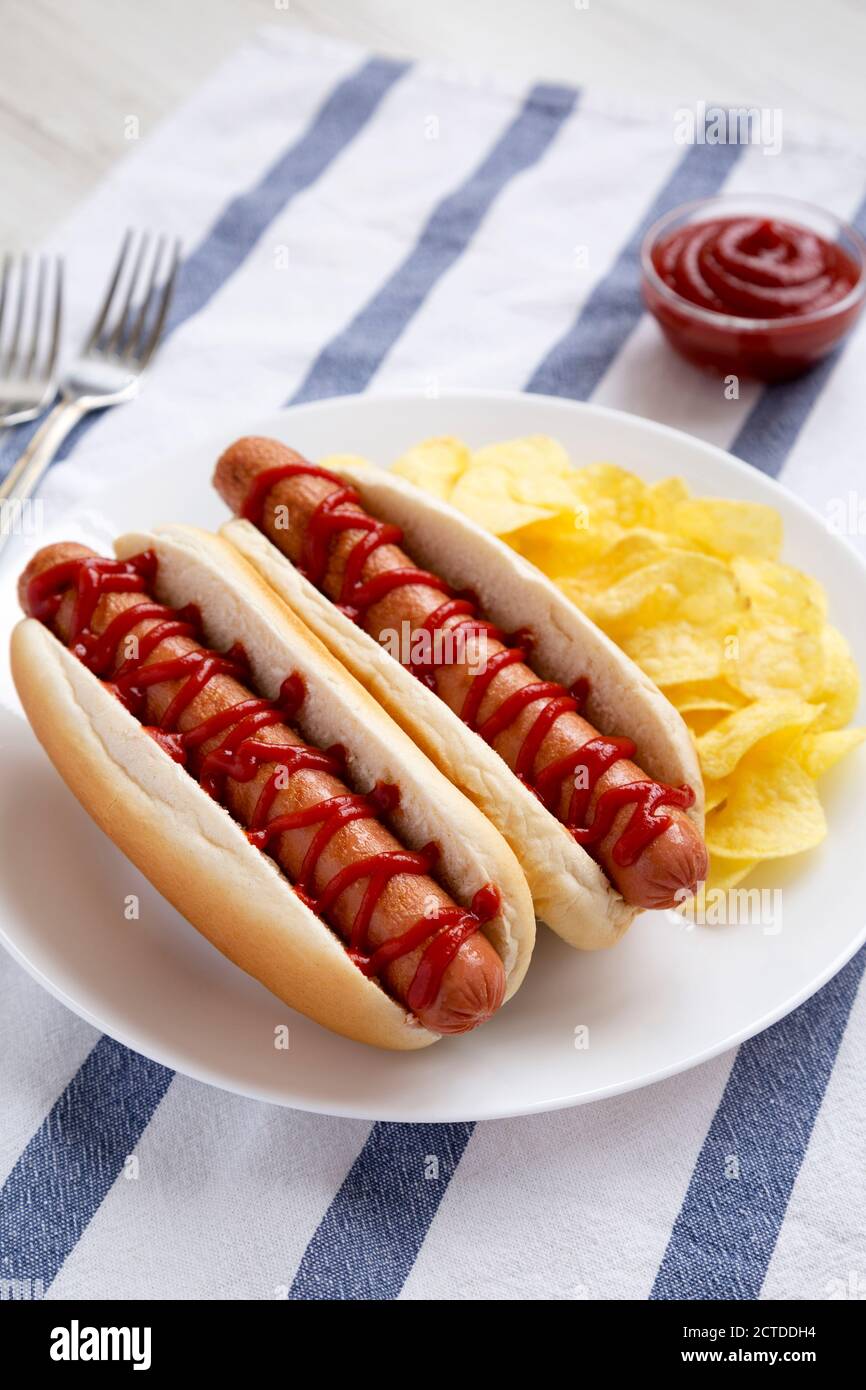 Tasty American Hot Dog with Potato Chips on a white plate, side view