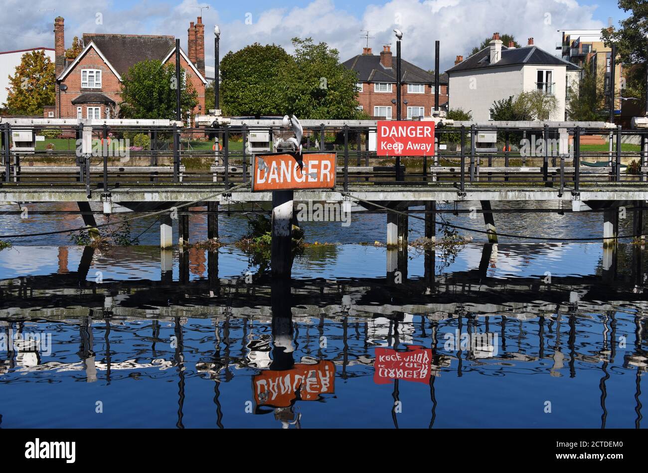 Danger signs reflected in the still blue waters of the Kennet in Reading, Berkshire Stock Photo
