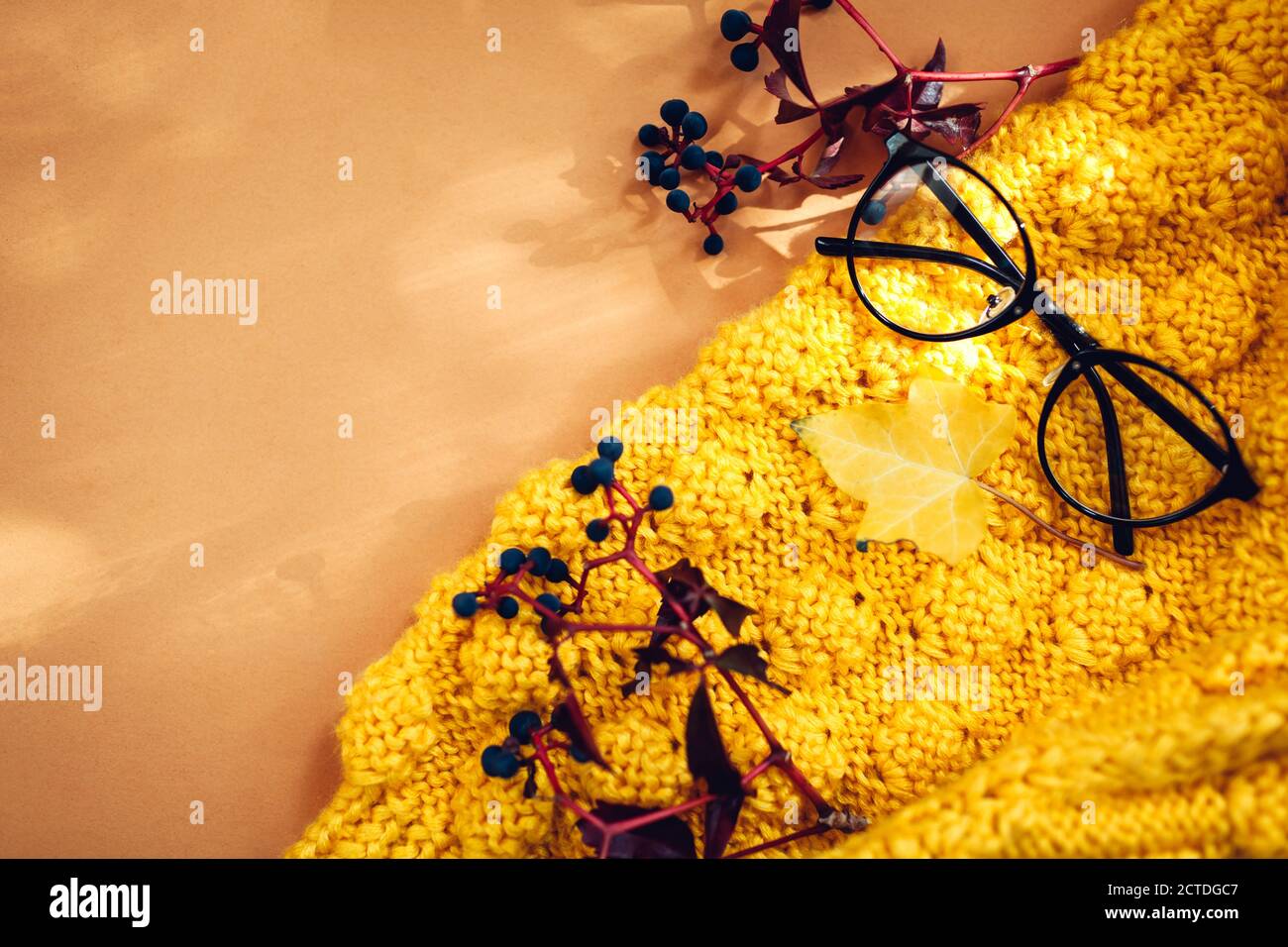 Autumn background with leaves, yellow sweater and glasses. Flat lay hygge composition. Space Stock Photo
