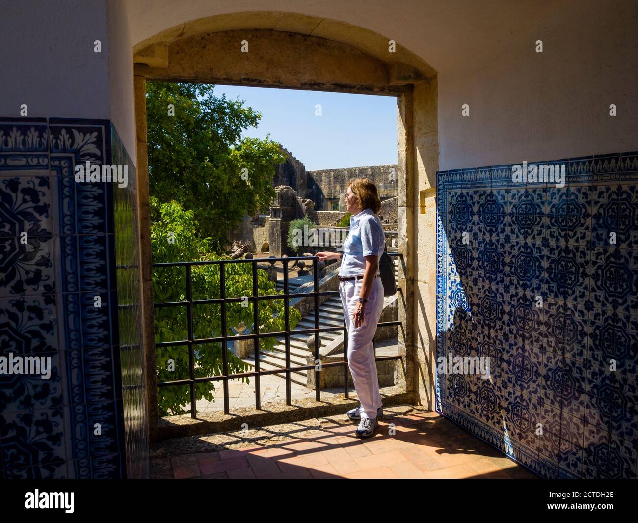 Tourist seeing the external gardens of the Templar Castle in Tomar from an internal window decorated with hand painted tiles. Tomar - Portugal Stock Photo