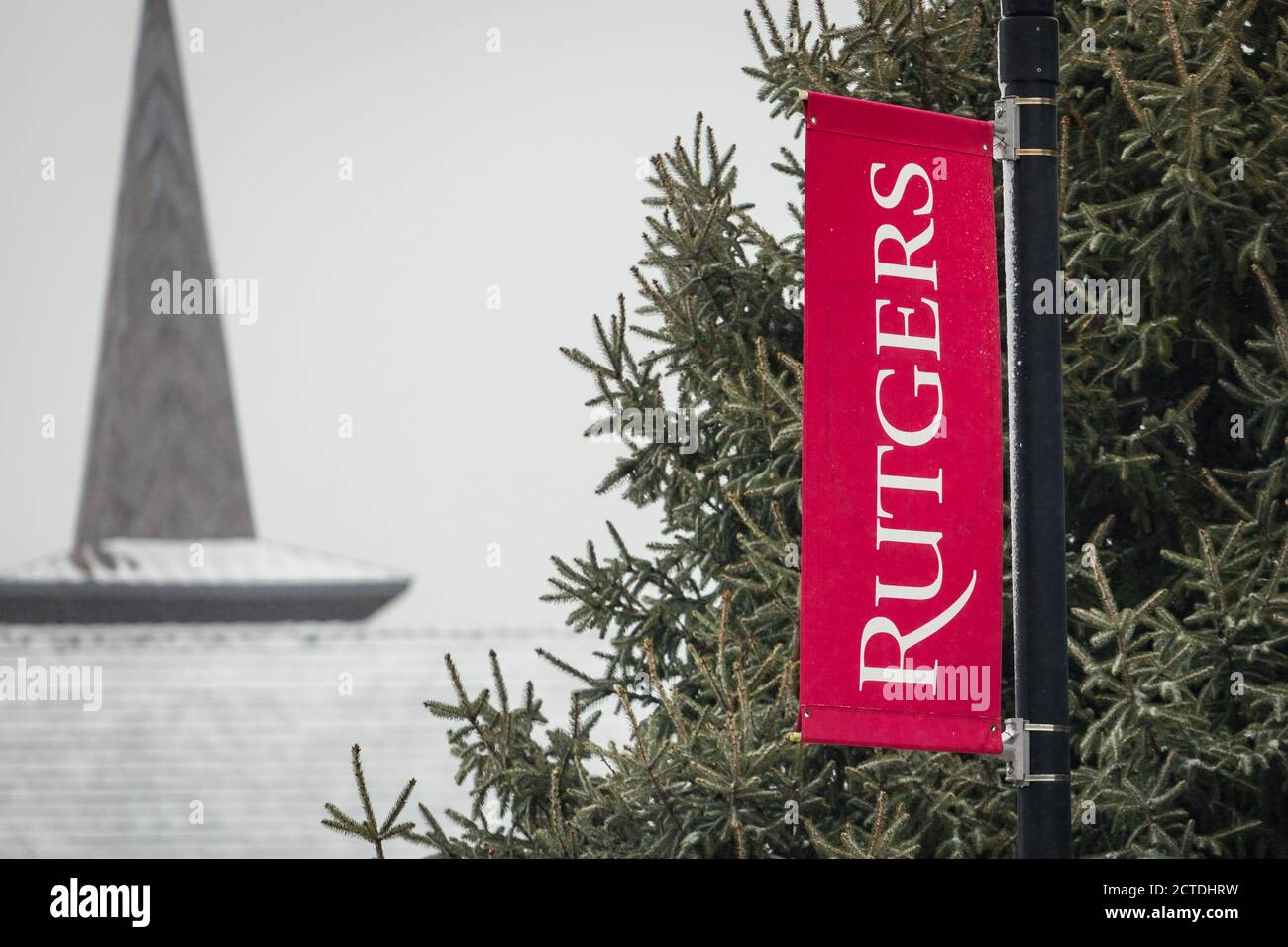 Rutgers university logo flag with backdrop of evergreen pine trees in 