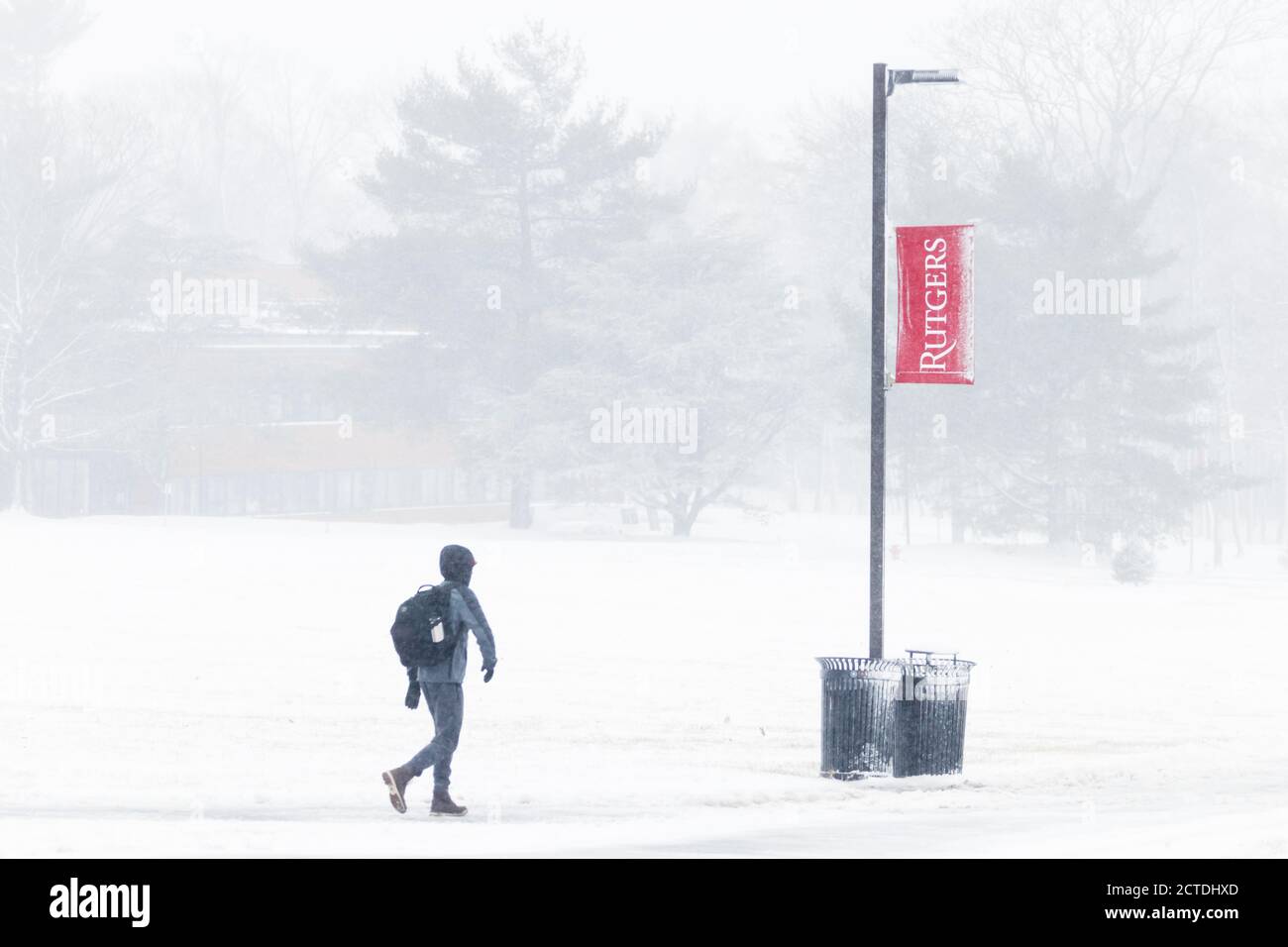 Rutgers University banner in a storm of snow, sleet, and frozen rain; student on campus in foreground. Stock Photo