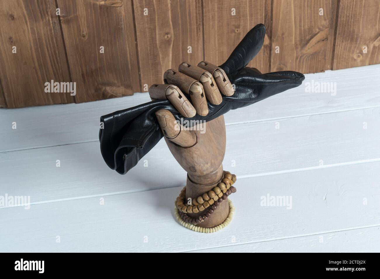 a leather glove held by a wooden hand on a table Stock Photo