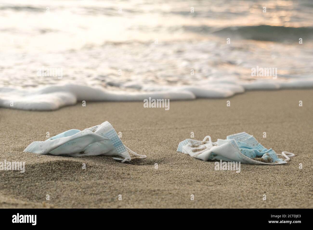 Medical face masks discarded on sea shore,covid19 pandemic disease pollution Stock Photo