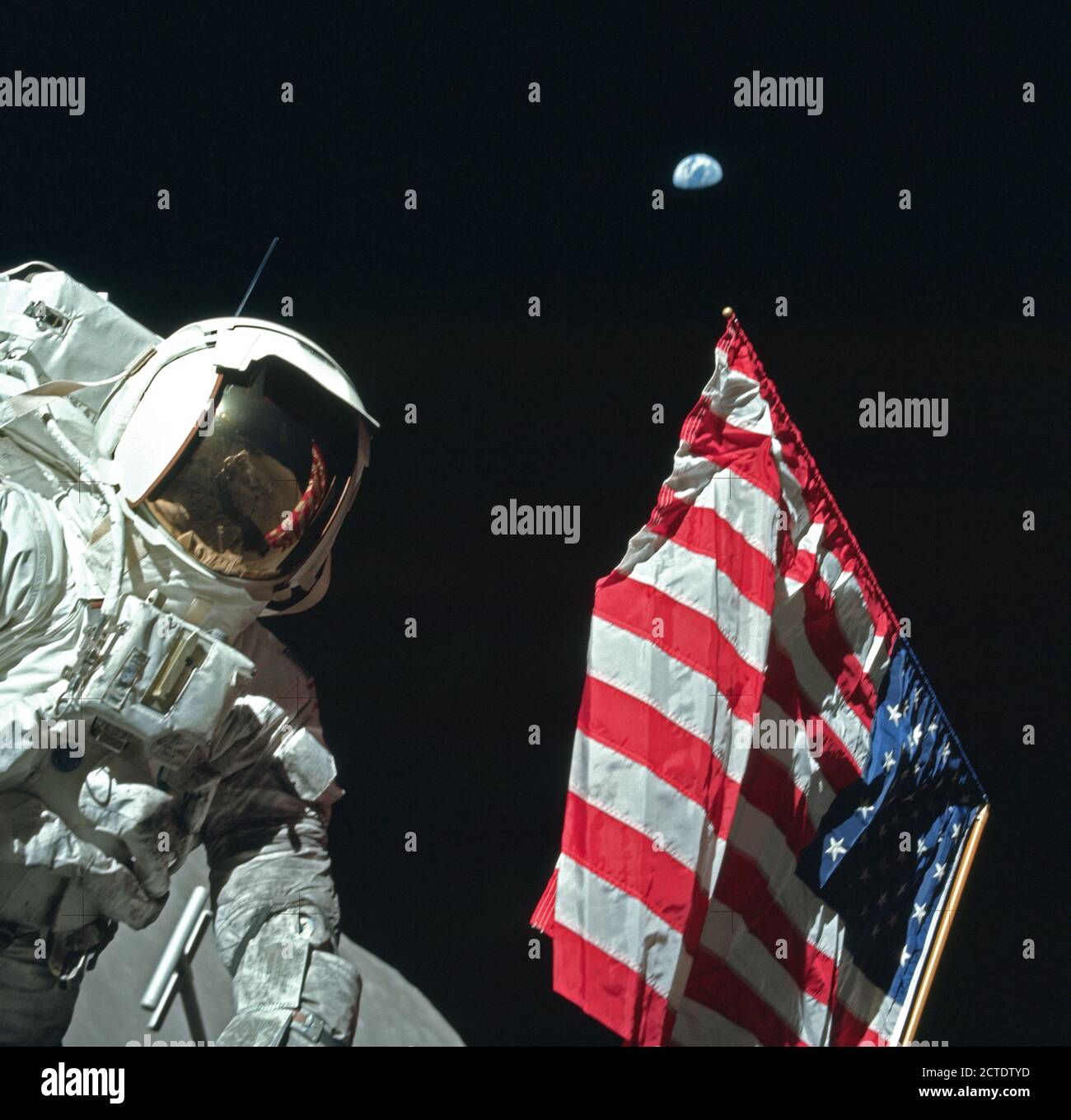 Astronaut Harrison Schmitt poses on the Lunar surface next to an American flag during Apollo 17. (moon surface seen on bottom of image) Stock Photo