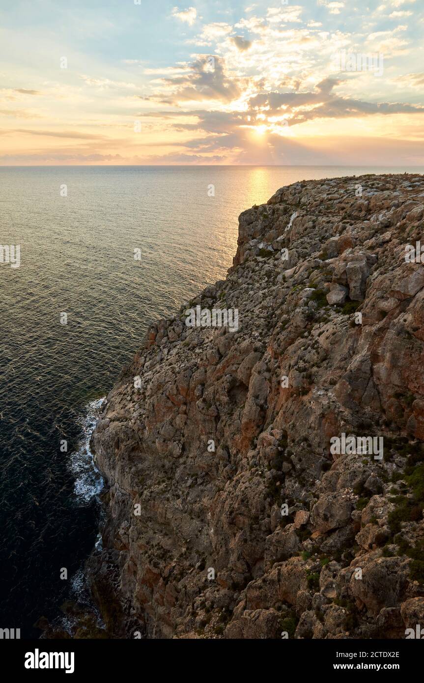 Sunset from the cliffs of Cap de Barbaria cape with mediterranean sea, sunrays and clouds in Formentera (Balearic Islands, Spain) Stock Photo