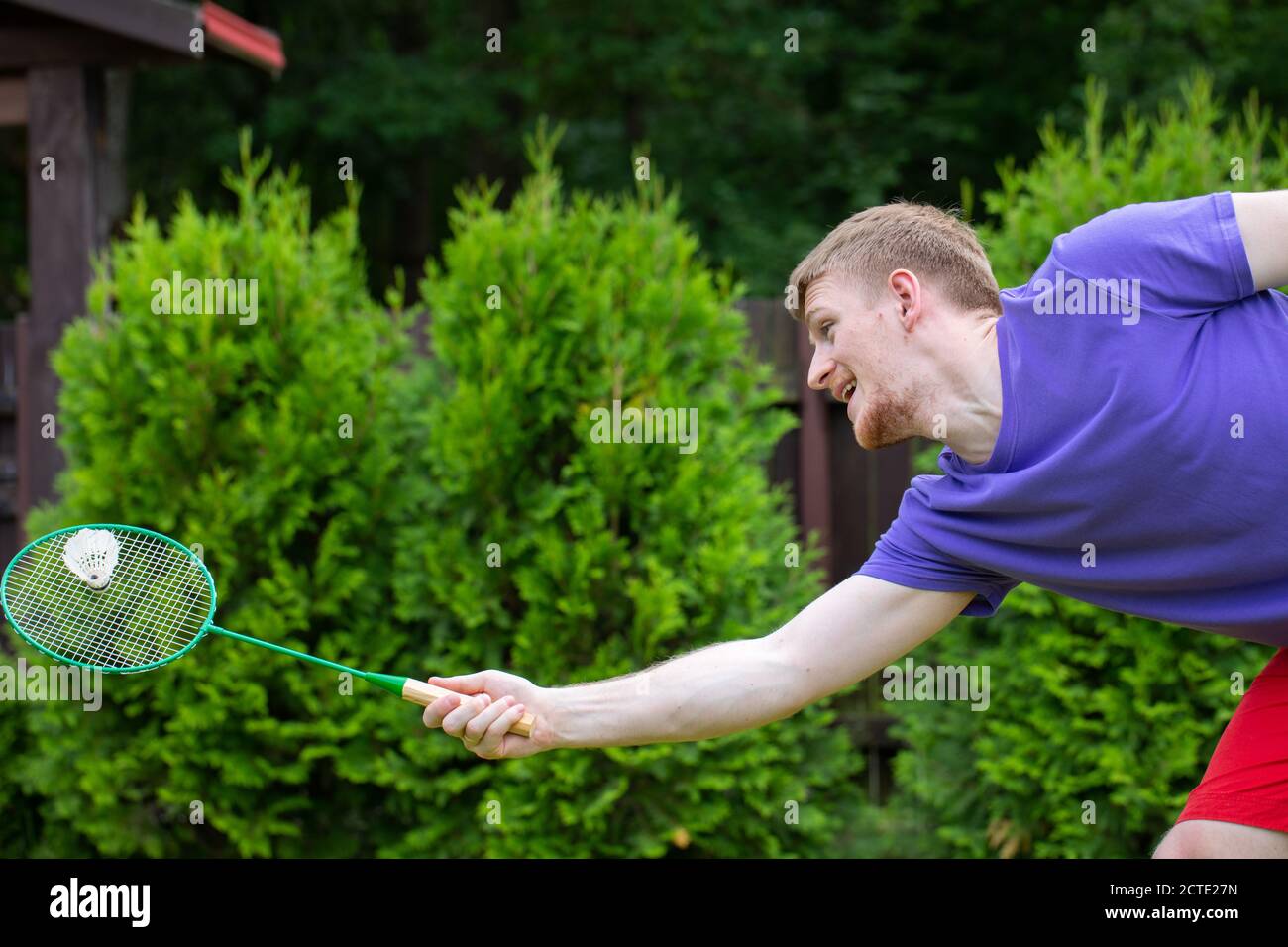 Badminton player with racket in action. Young guy playing badminton  outdoors Stock Photo - Alamy
