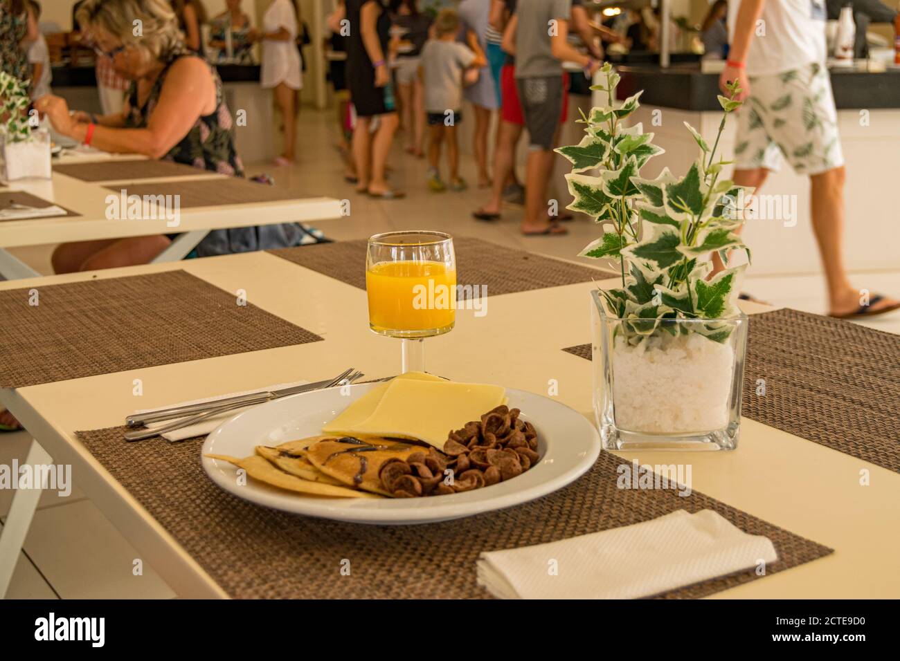 Breakfast in hotel with orange juice, cheese chocolate pancakes and cereals. People or tourists walking on the hotel restaurant at morning time. Stock Photo