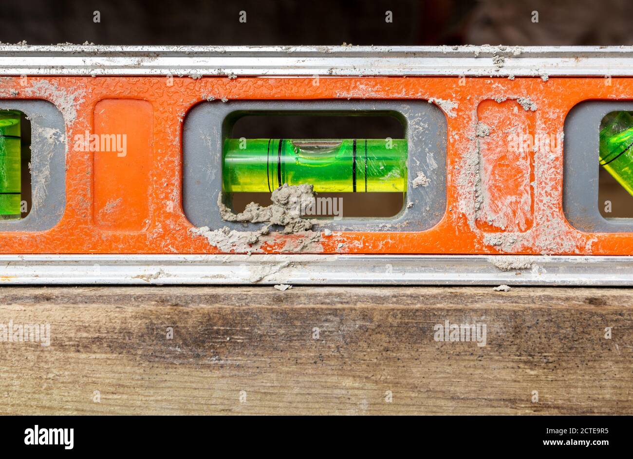 Dirty orange tool level in use, closeup. Also know as Tubular Spirit Level or Bubble Level. Used to find a true horizontal or vertical plane. Stock Photo